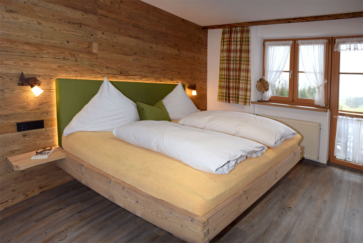Großes Doppelbett an einer Holzfront